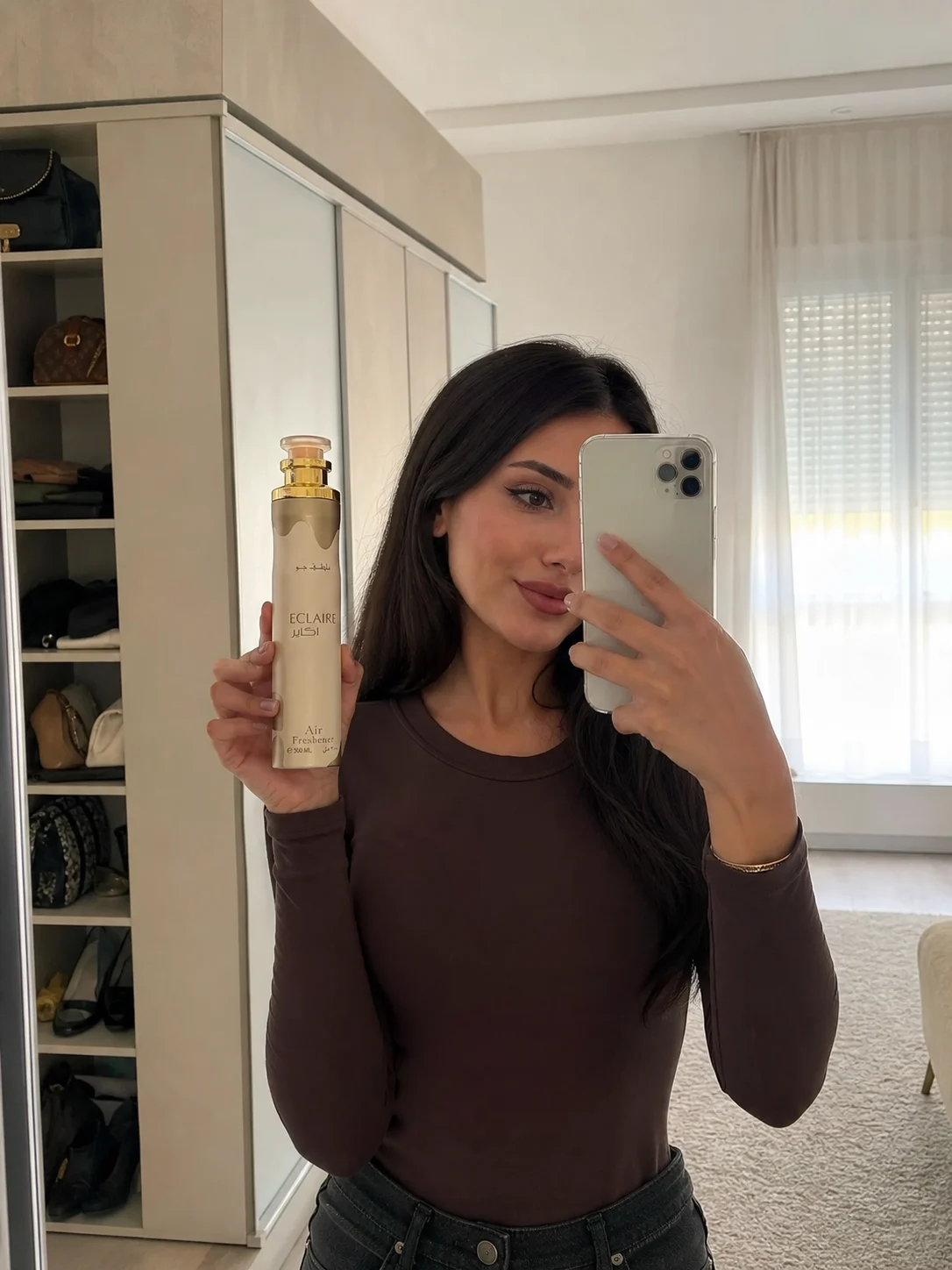Ambientador Eclaire de Lattafa, spray de 300 ml, sostenido en la mano frente al espejo
